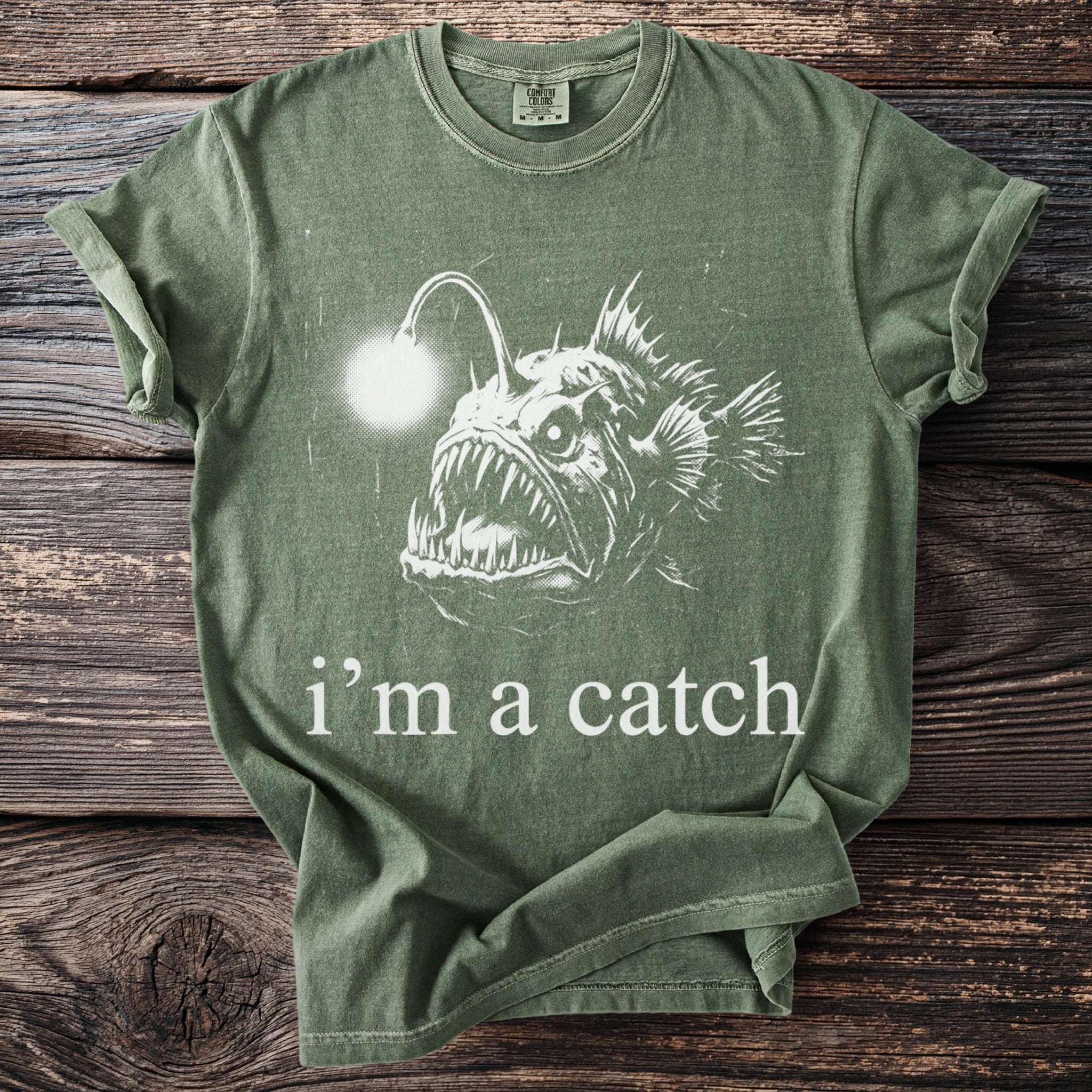Green t-shirt with a white drawing of an anglerfish and text saying "i'm a catch."
