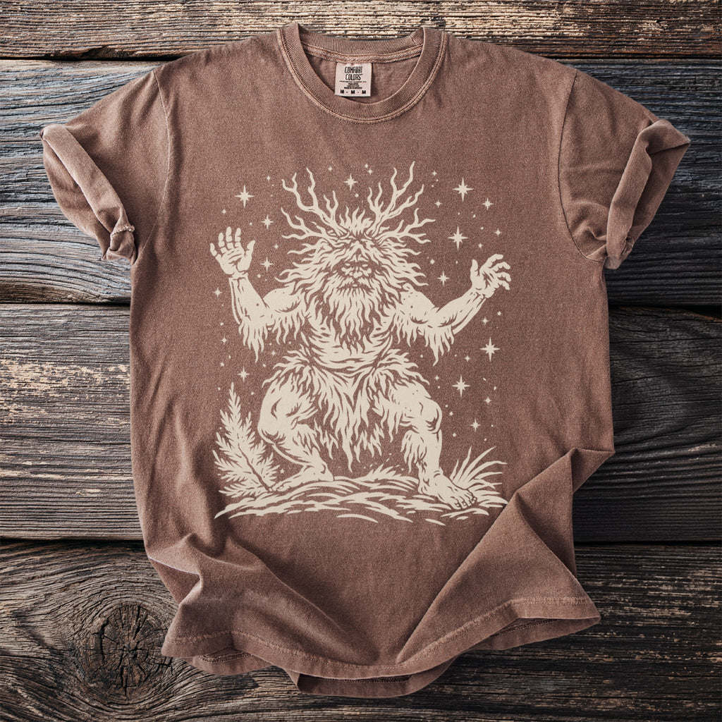 Brown t-shirt with a cream illustration of a horned, bearded creature surrounded by stars.