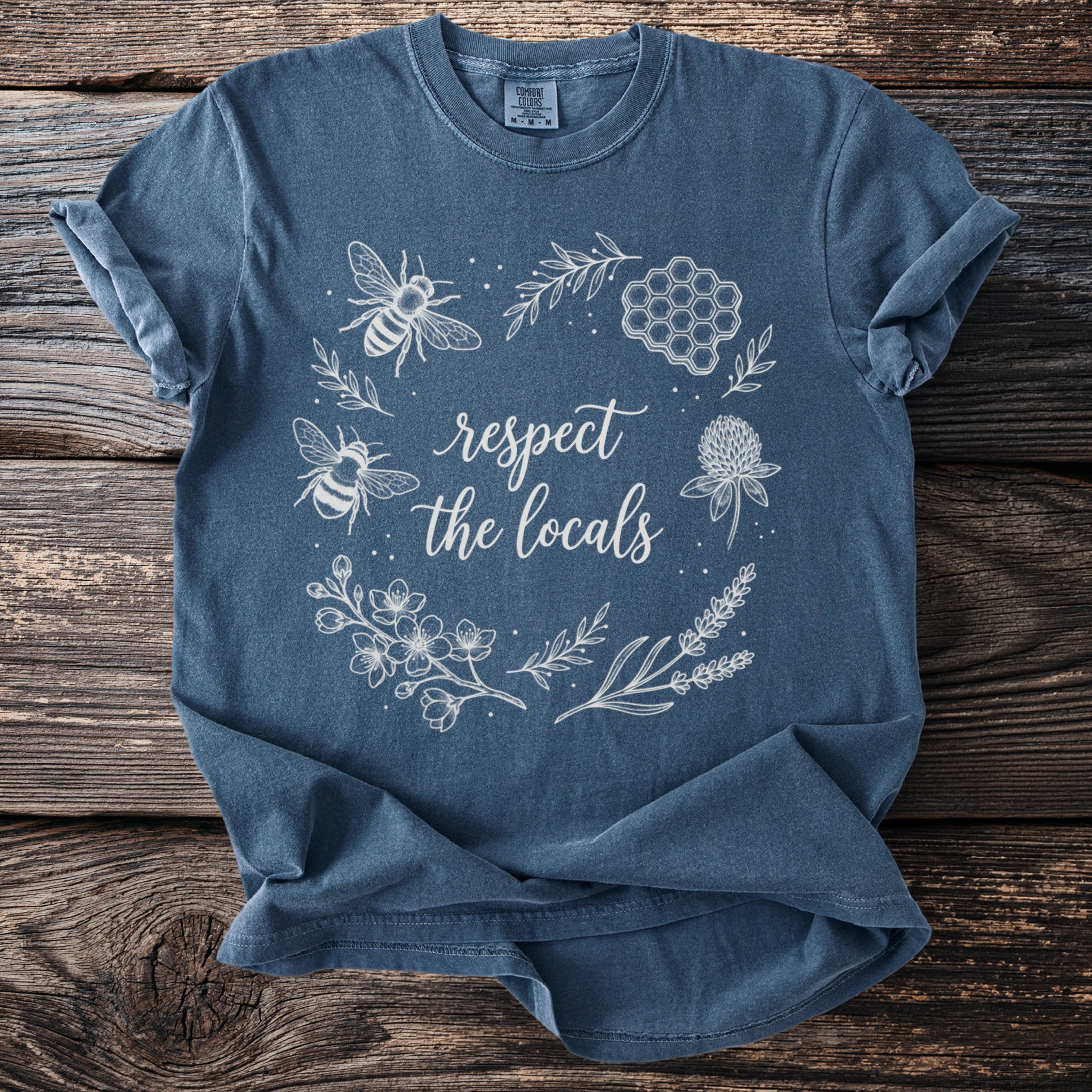 Blue t-shirt with white line art of bees, honeycomb, and flowers.