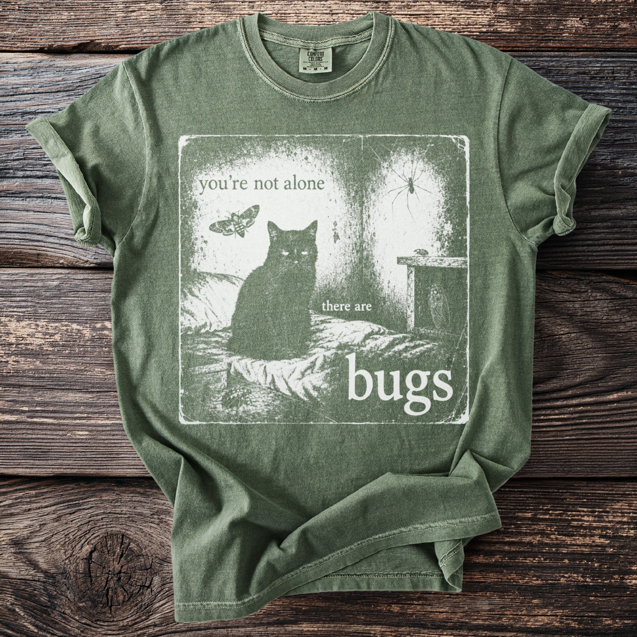 Green t-shirt graphic: black cat, moth, spider, and bugs with text "you're not alone there are bugs".