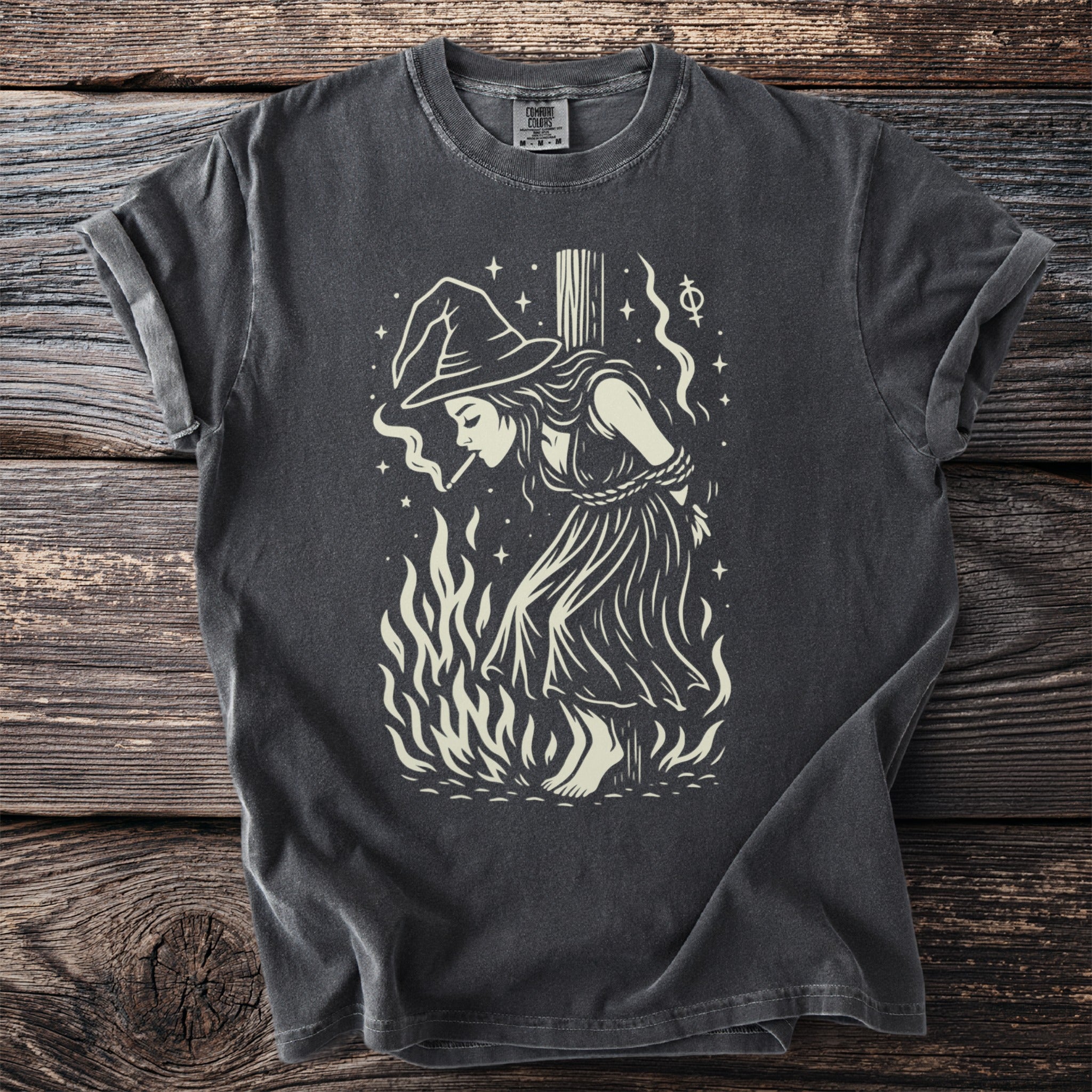 Witch tied to a stake, smoking, surrounded by flames and stars.