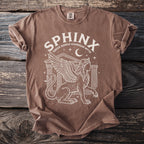 Brown t-shirt with white graphic of a sphinx, columns, moon, and stars.
