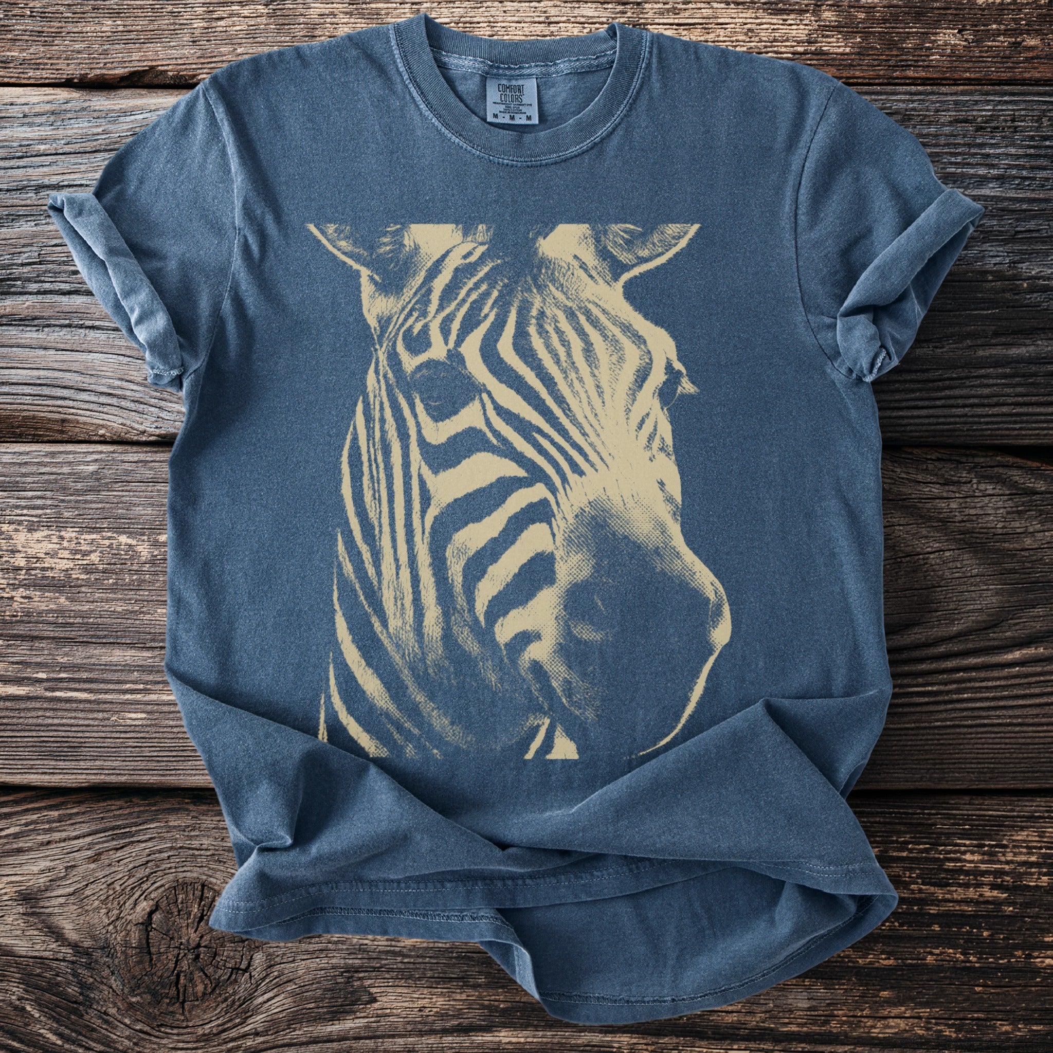 Blue t-shirt with a tan zebra head graphic and a comfort colors tag.