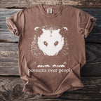 Brown t-shirt with white opossum graphic and text "possums over people".
