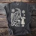 Dark grey t-shirt with a cream graphic of Krampus and a child with snowflakes.