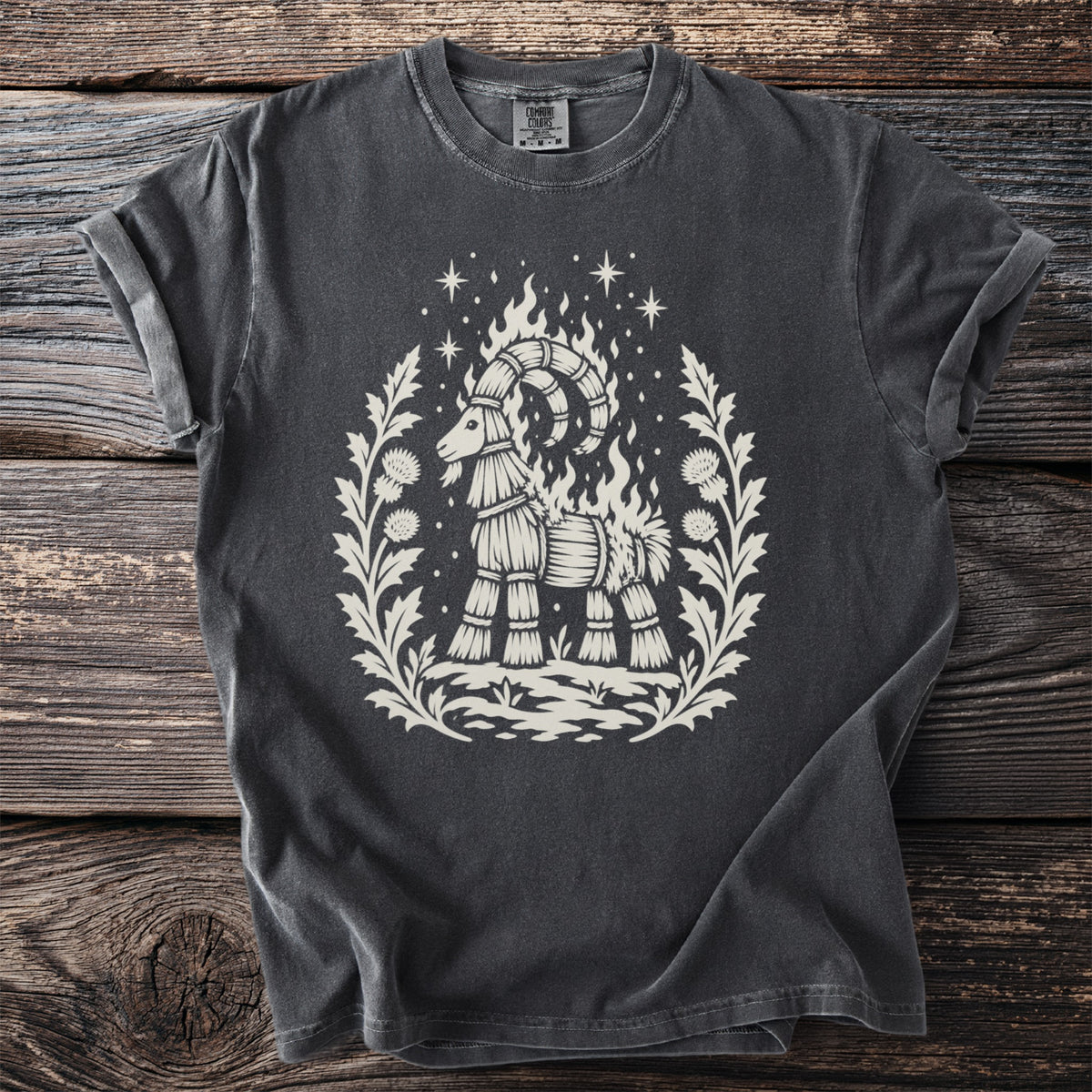 Dark grey t-shirt featuring a cream graphic of a straw goat with flames and stars.