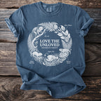 Blue t-shirt with "Love the Unloved" and illustrations of odd creatures in a circular design.
