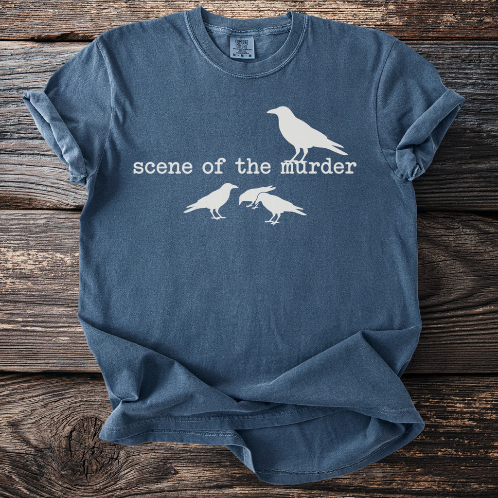 Blue t-shirt with white graphic of crows and text "scene of the murder".