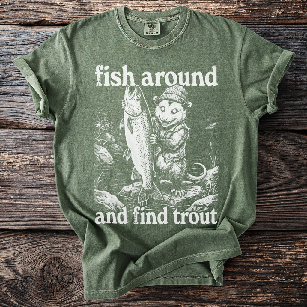 Green t-shirt graphic of possum holding large fish with text "fish around and find trout".