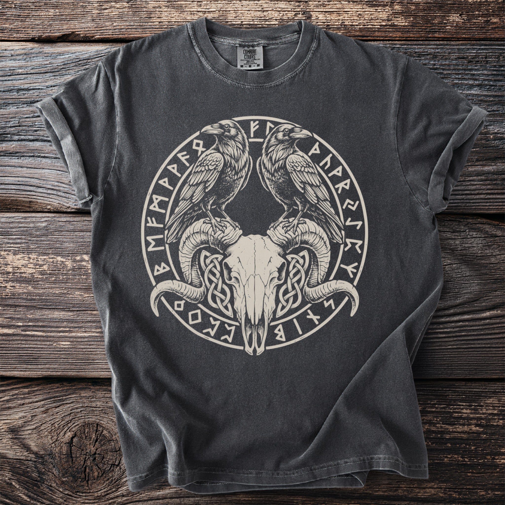 Dark t-shirt featuring a circular design with two ravens over a ram skull and runes.