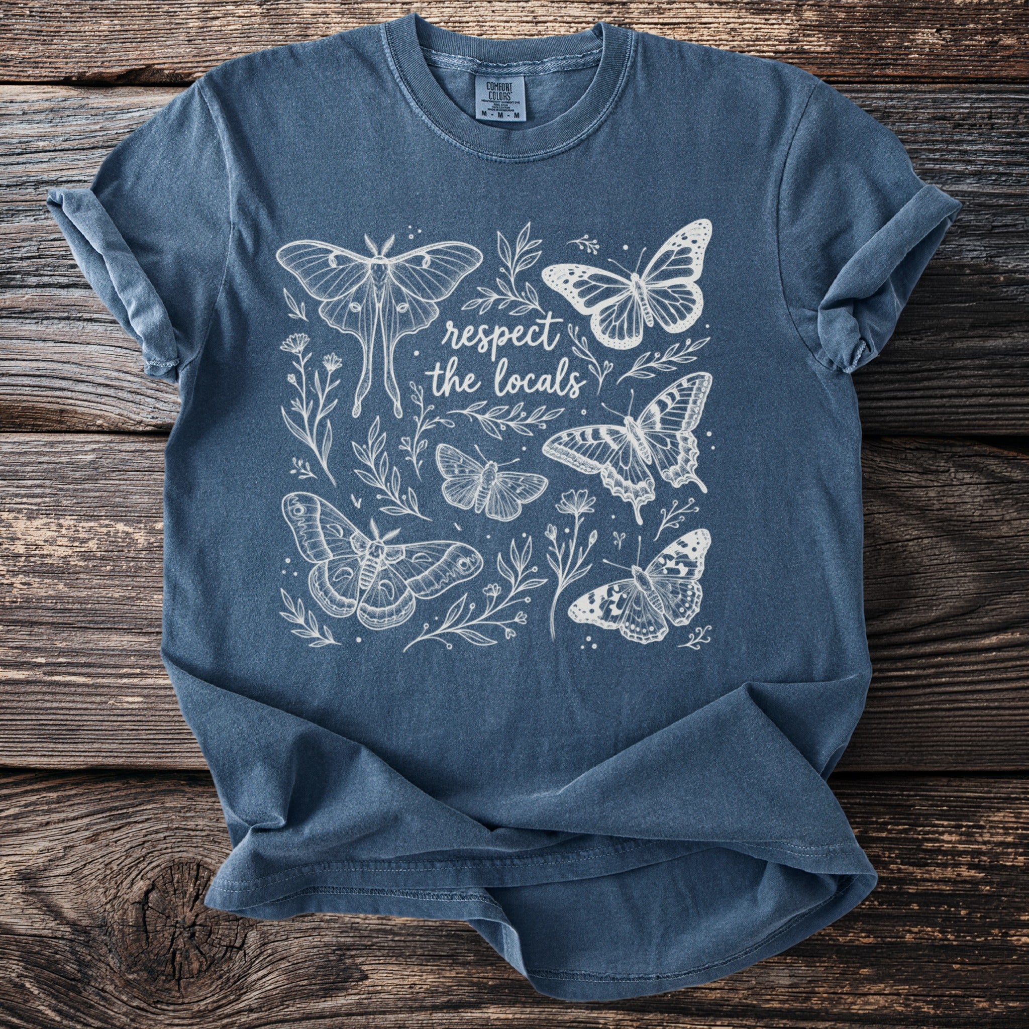 Blue t-shirt with white outline drawing of butterflies and text "respect the locals".