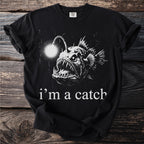 Black t-shirt with a graphic of an anglerfish and text "i'm a catch."