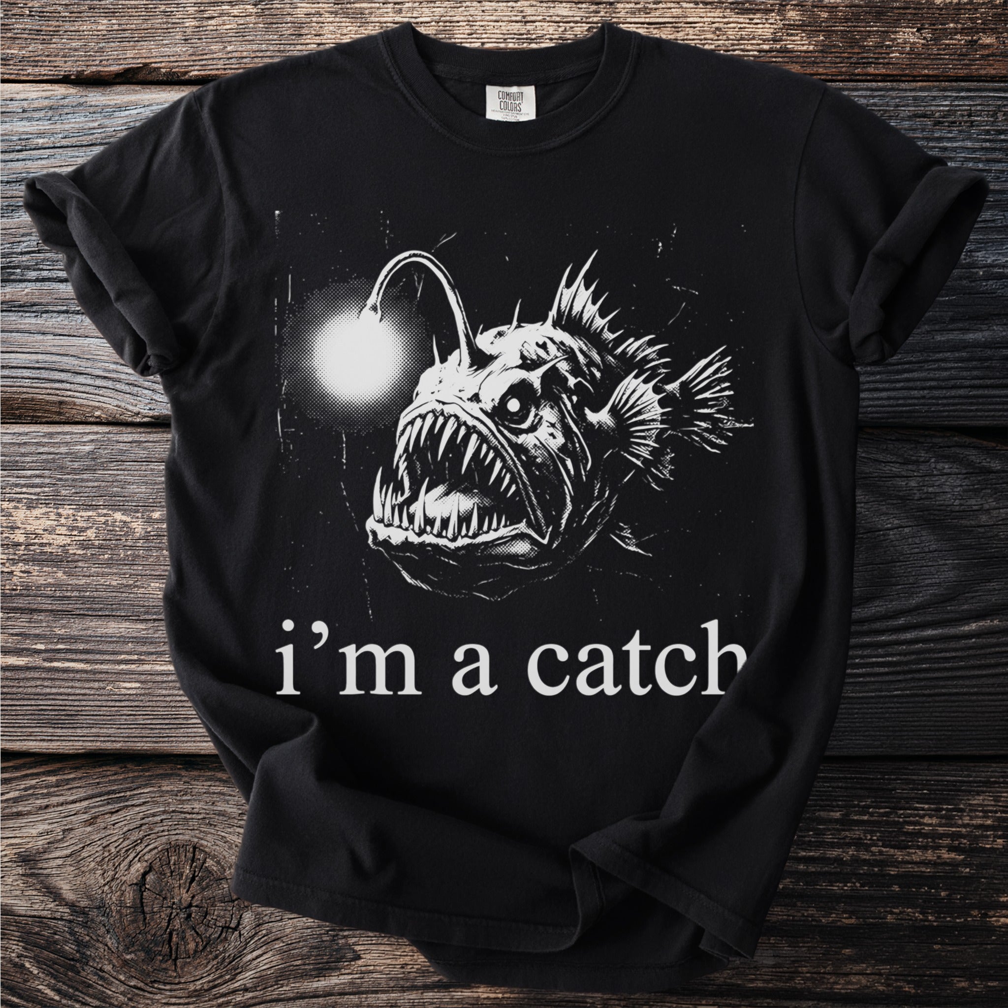 Black t-shirt with a graphic of an anglerfish and text "i'm a catch."