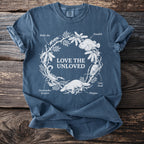 Blue t-shirt with "Love the Unloved" text and illustrations of animals from a nature wreath.