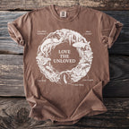 Brown t-shirt with circle design of cave creatures and plants, text "LOVE THE UNLOVED".