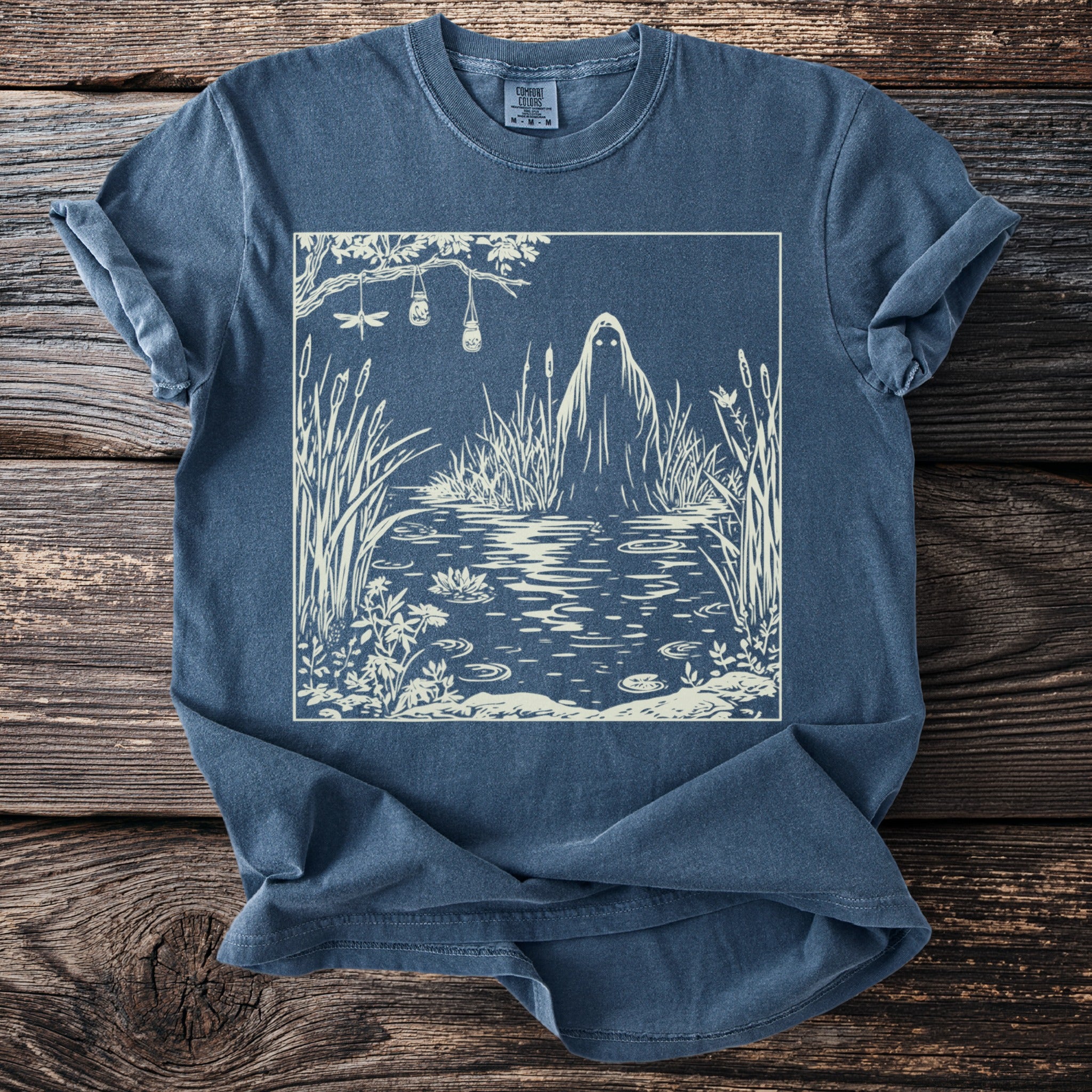 T-shirt with a white illustration of a ghost in a swamp with dragonflies and hanging jars.