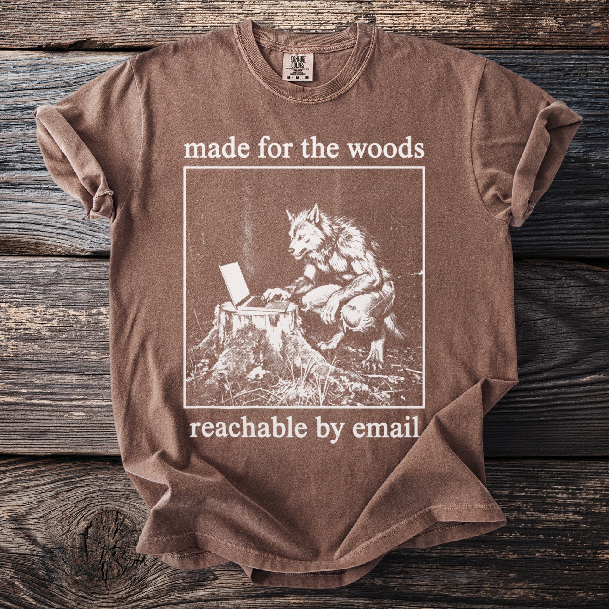 Brown t-shirt with a graphic of a werewolf at a laptop on a stump, text reads "made for the woods reachable by email".