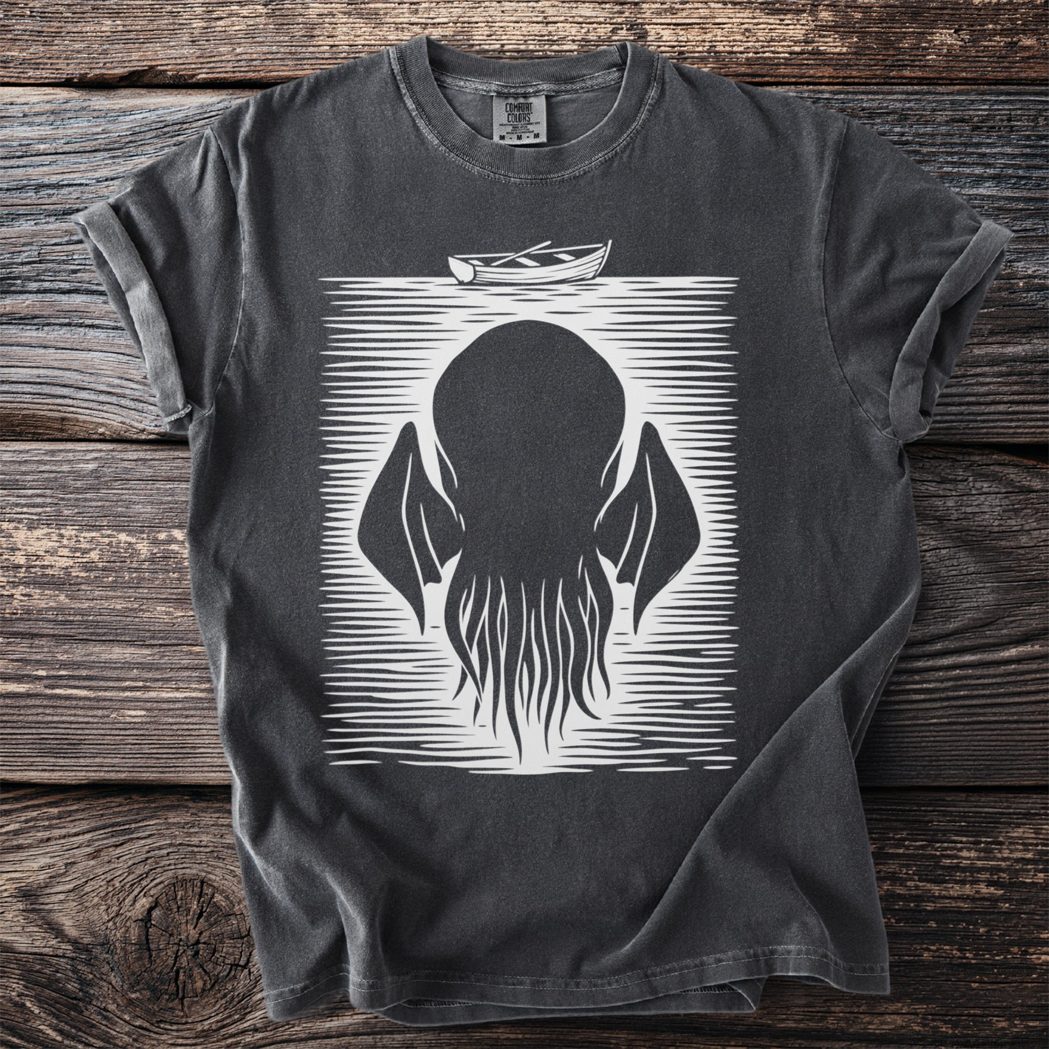 Dark t-shirt with a white graphic of a tentacled creature and a rowboat.