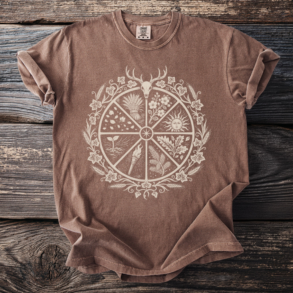 Brown t-shirt with a circular design featuring a deer skull, sun, torch, and plants.