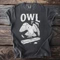 Dark grey t-shirt with white "OWL" text and barn owl graphic.