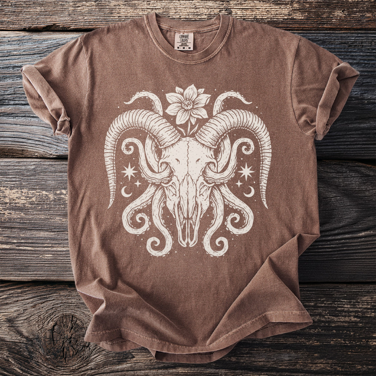 Brown t-shirt with a cream-colored ram skull, tentacles, flower, stars, and moon graphic.
