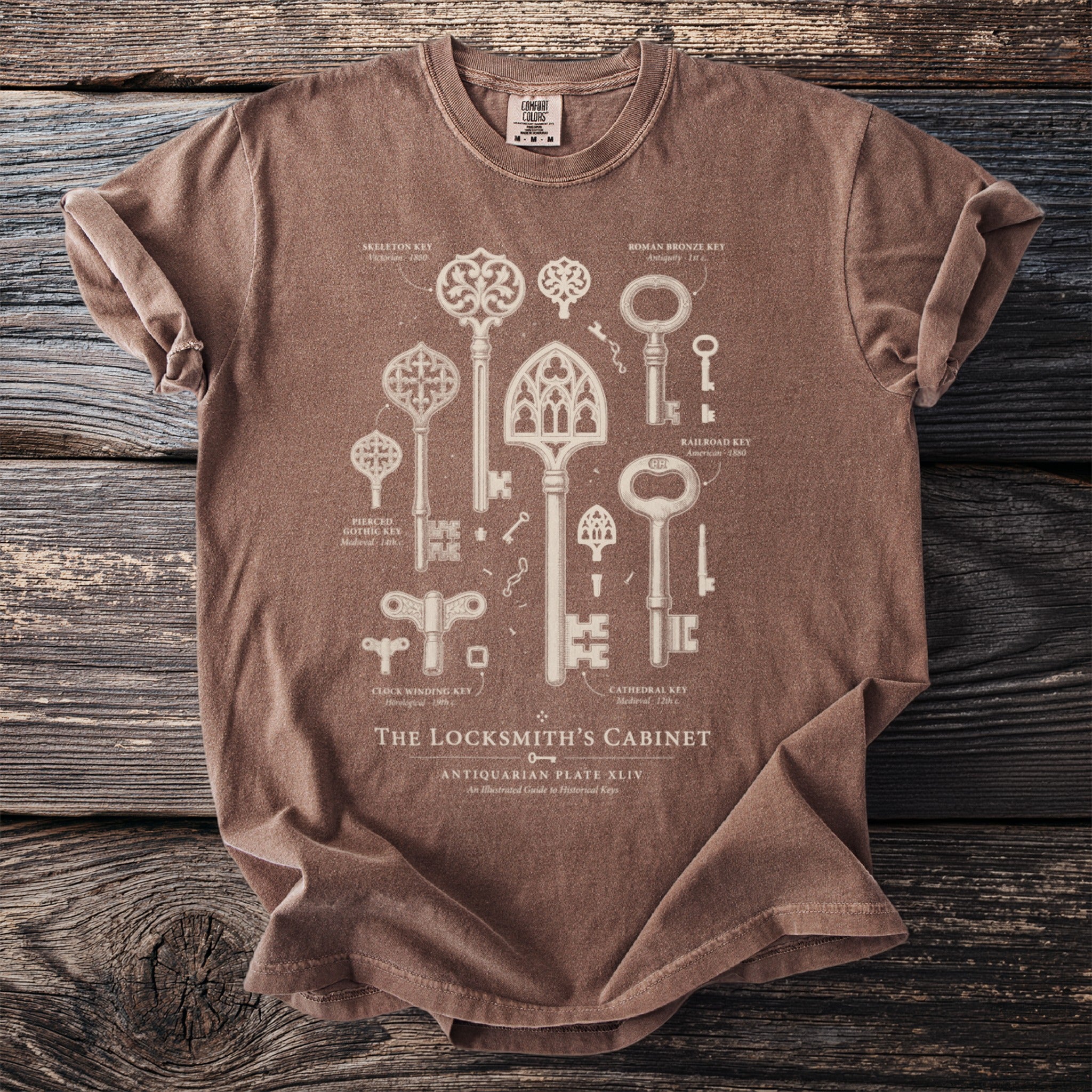 Brown t-shirt with illustration of "The Locksmith's Cabinet" historical keys.