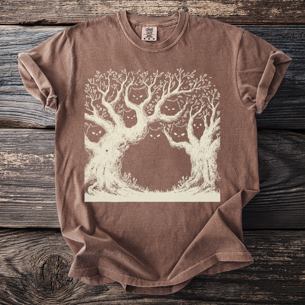 Brown t-shirt with a cream line drawing of spooky trees with cat faces.