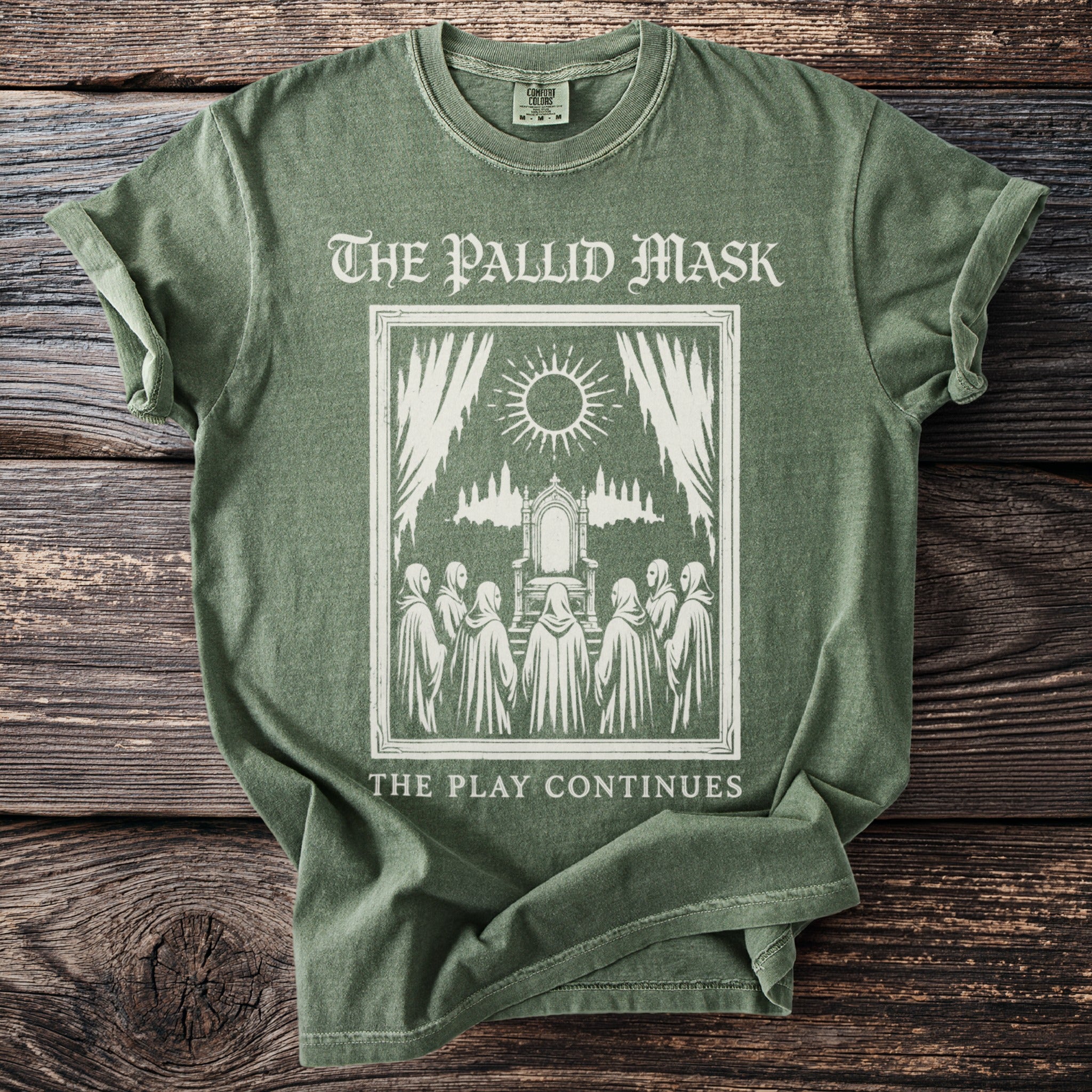 Green t-shirt with "The Pallid Mask" graphic and "The Play Continues" text.