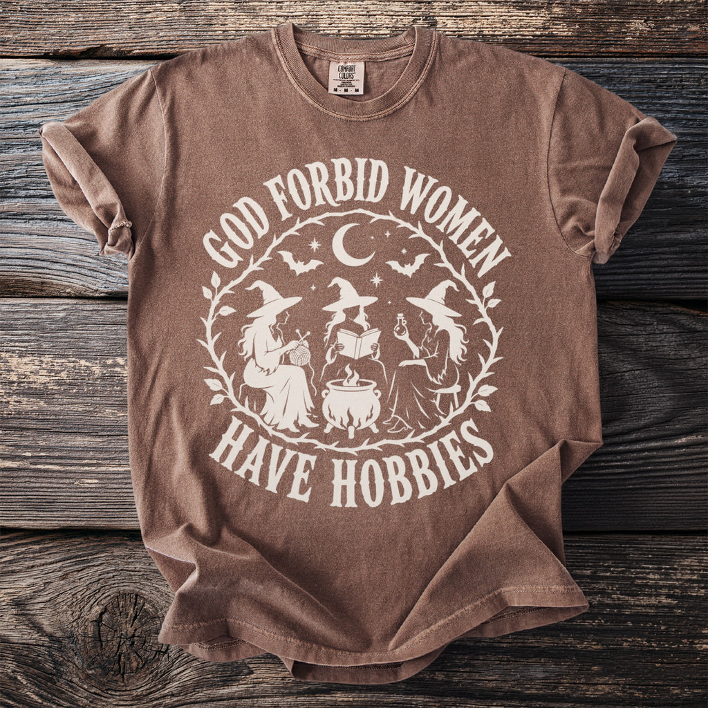 Brown t-shirt featuring white text and graphic of three witches around a cauldron.