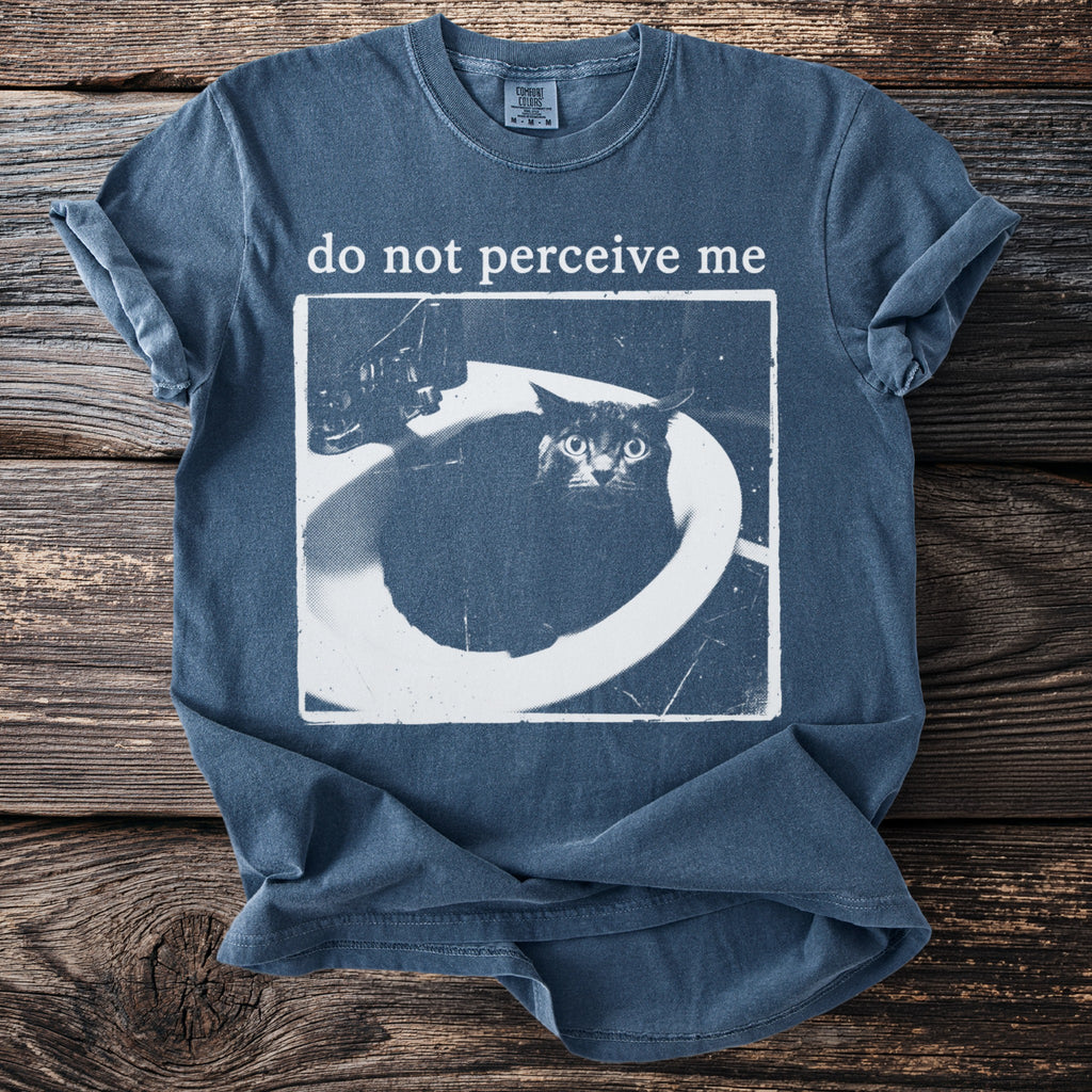 T-shirt with white text "do not perceive me" over a cat in a sink.