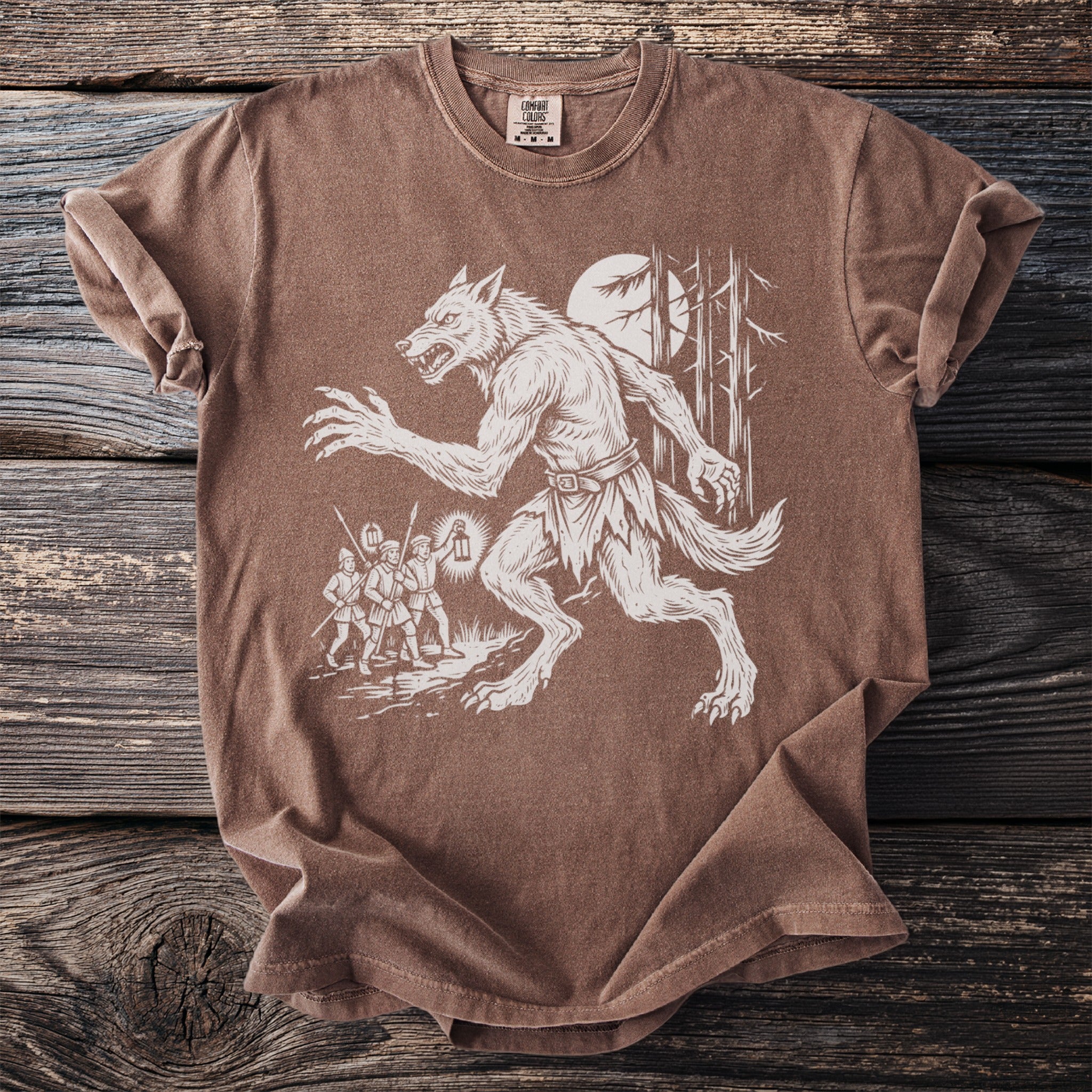 Brown t-shirt with white print of a werewolf chasing three men with lanterns through a forest.
