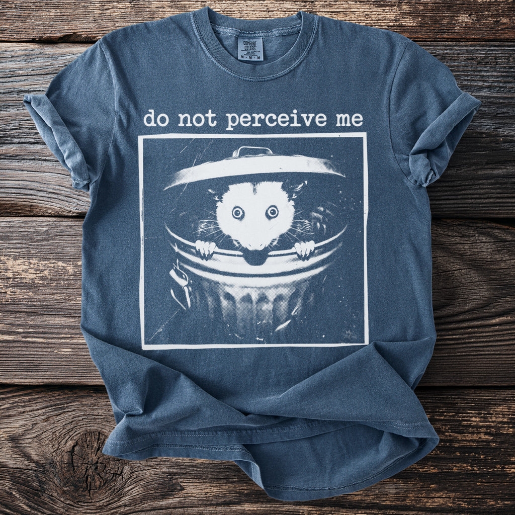 Blue t-shirt with graphic of opossum in trash can and text "do not perceive me".