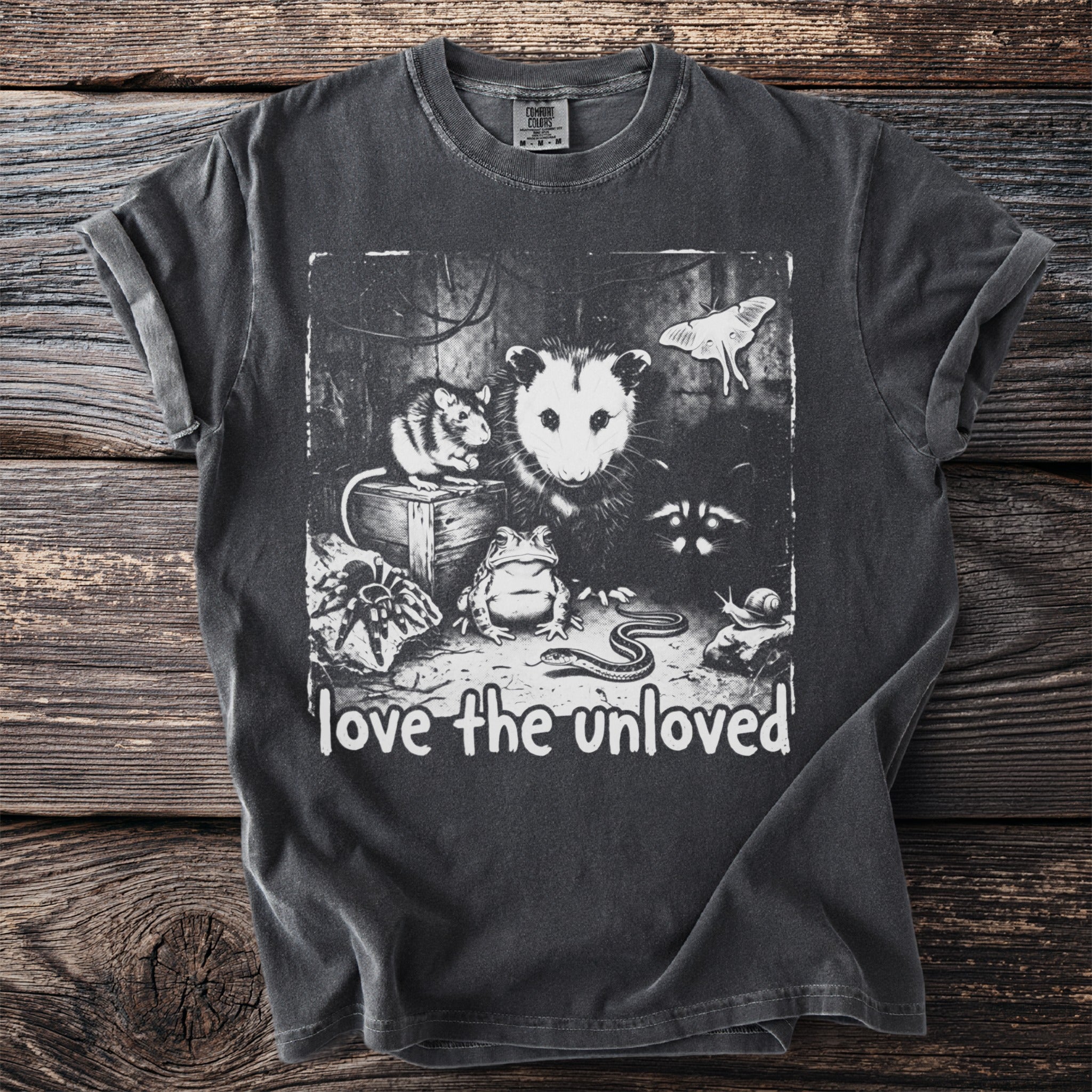 Dark t-shirt with black and white graphic of various creatures and "love the unloved" text.