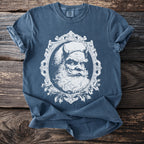Blue t-shirt with a white distressed graphic of a horned, scowling Santa within an ornate frame.