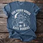 Blue t-shirt with white text "God forbid women have hobbies" and cat graphics.