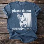 Blue t-shirt with a kitten peeking from behind a curtain, text says "please do not perceive me."