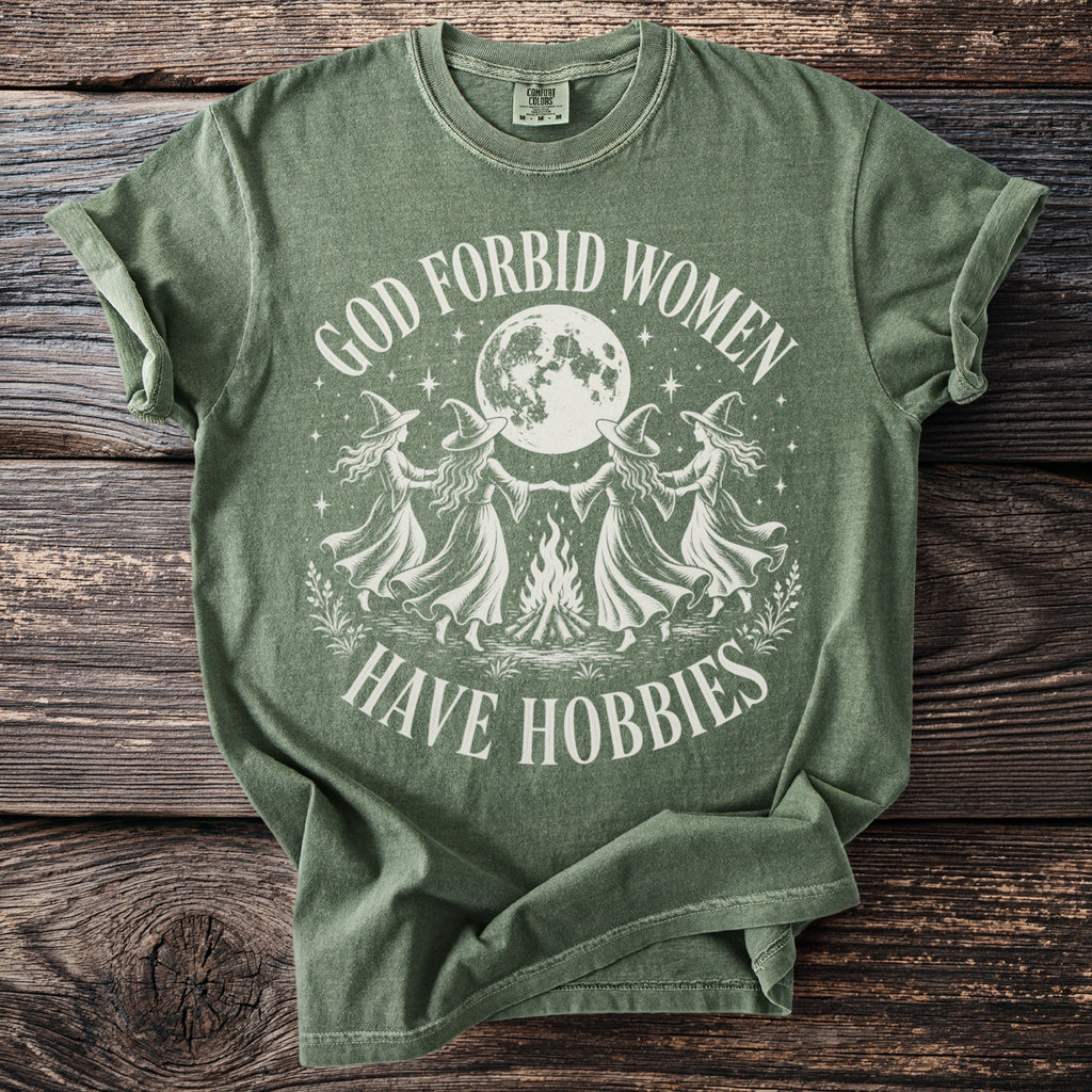 Green t-shirt with "God Forbid Women Have Hobbies" text and witch design