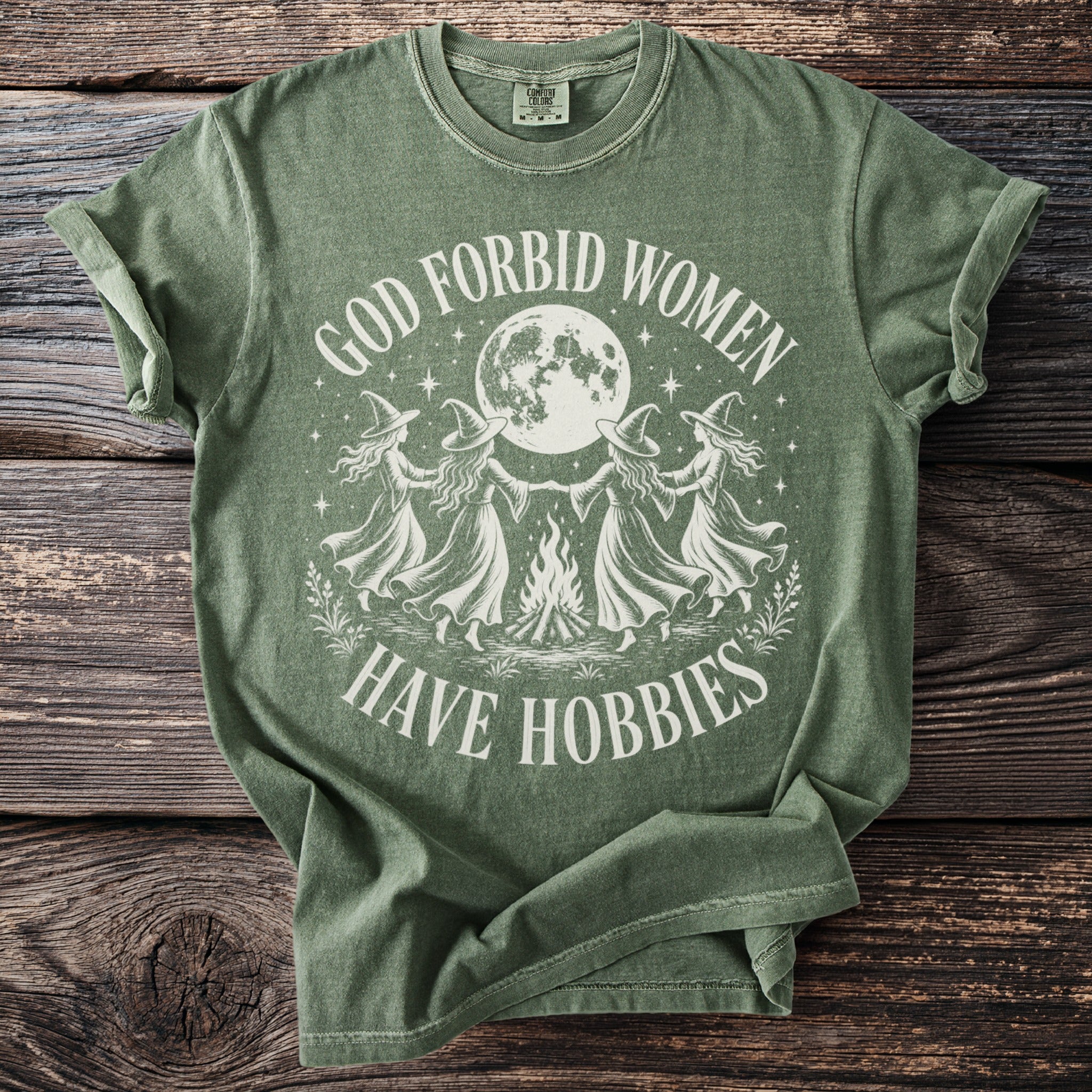 Green t-shirt with "God Forbid Women Have Hobbies" text and witch design