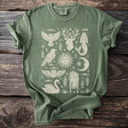 Green t-shirt with cream-colored mystical prints of celestial bodies and animals.
