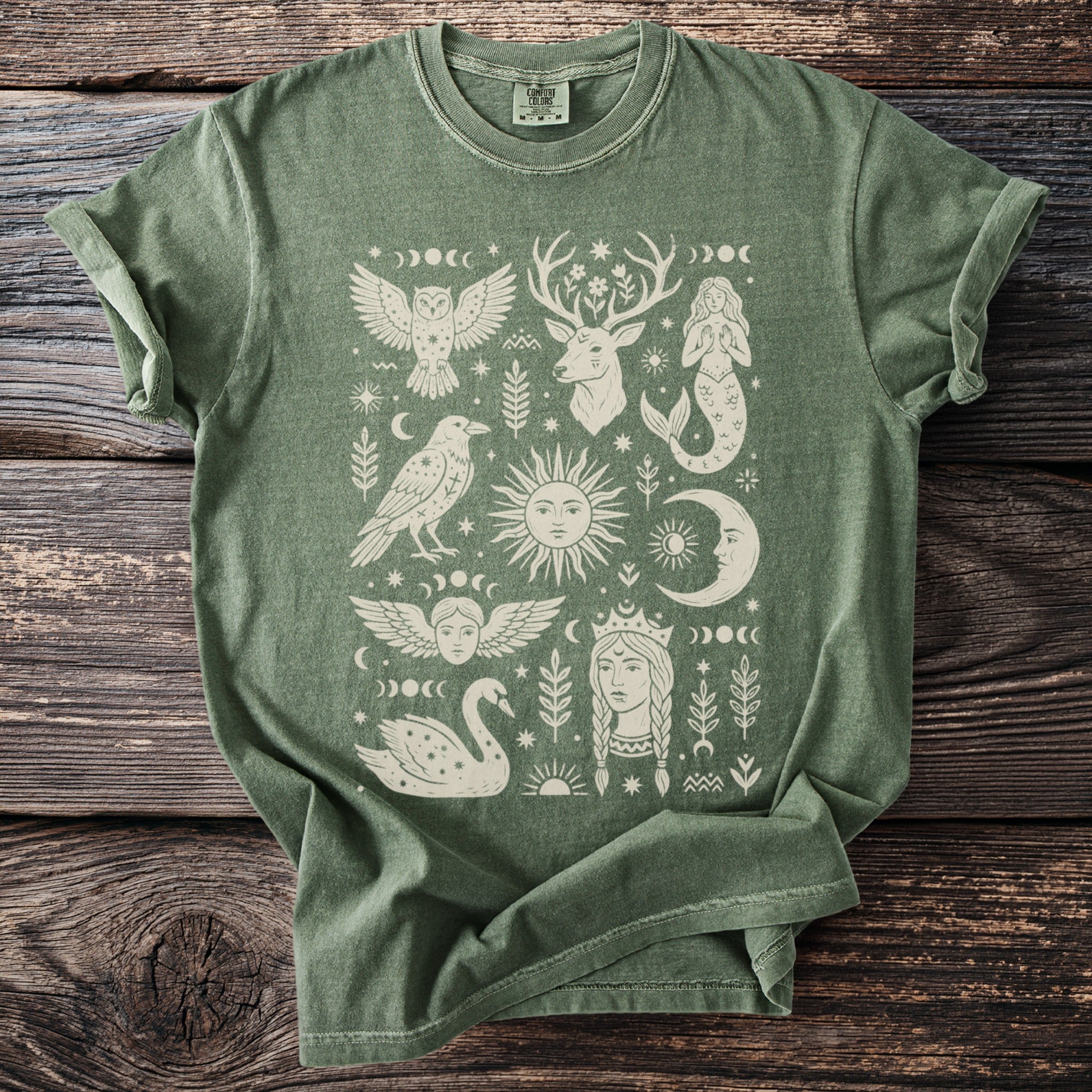 Green t-shirt with cream-colored mystical prints of celestial bodies and animals.