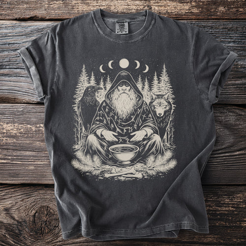T-shirt graphic shows a seated wizard surrounded by a wolf, raven, pine trees, and moon phases.