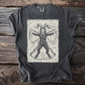 Pepper gray t-shirt with a cream folk-cut print: Krampus lies flat on his back in fresh snow, arms and hooves spread, making a snow angel.