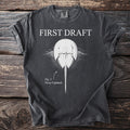 Dark grey t-shirt with "FIRST DRAFT" above a horseshoe crab labeled "Fig. 1: Never Updated."