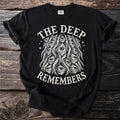 Black t-shirt with cream graphic of many eyes and text "THE DEEP REMEMBERS".