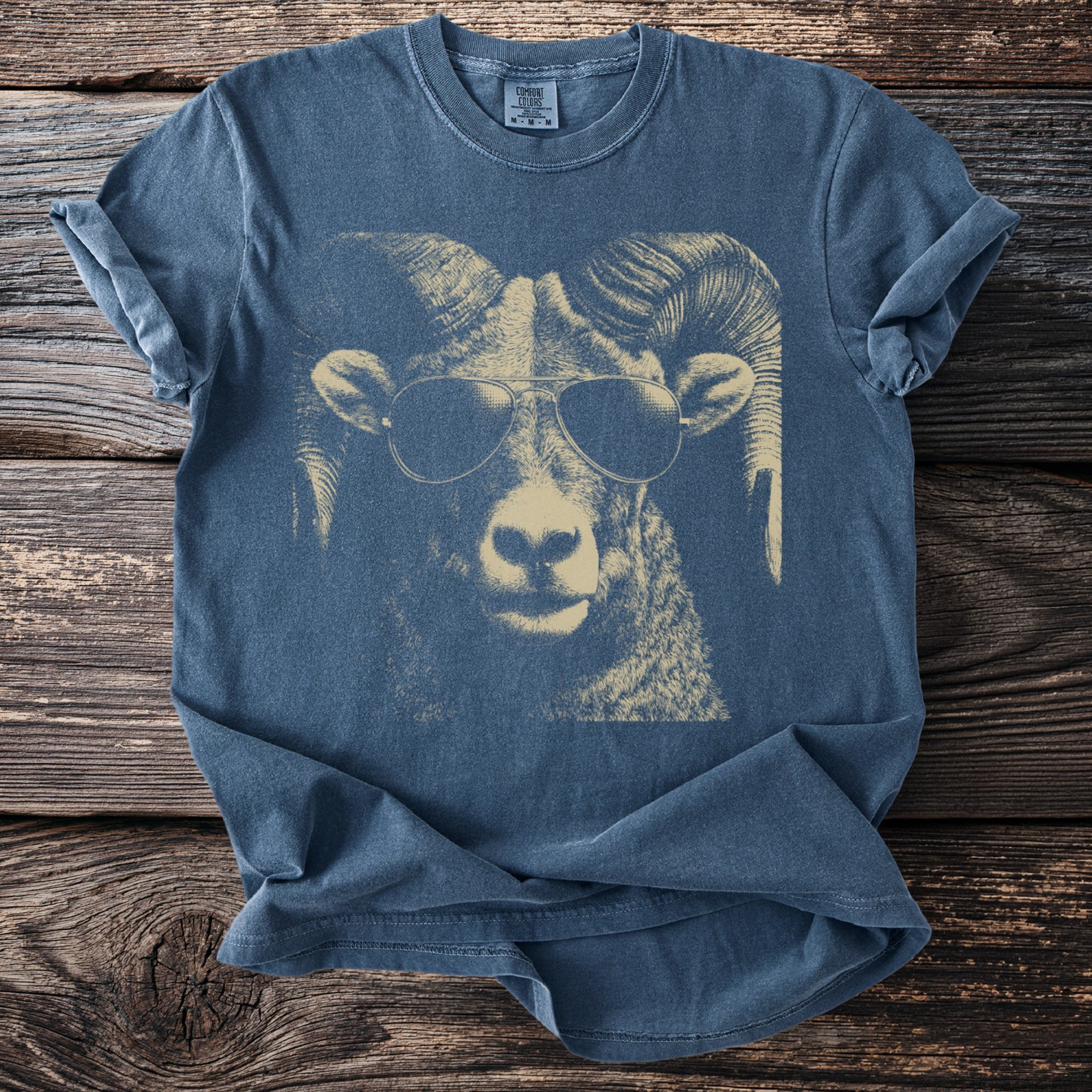 Blue t-shirt with a cream-colored graphic of a ram wearing sunglasses.