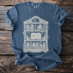 Blue t-shirt with a graphic of an apothecary shelf filled with potions, skulls, and a book.