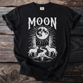 Black t-shirt with white graphic of the word "MOON" above a full moon and landscape.