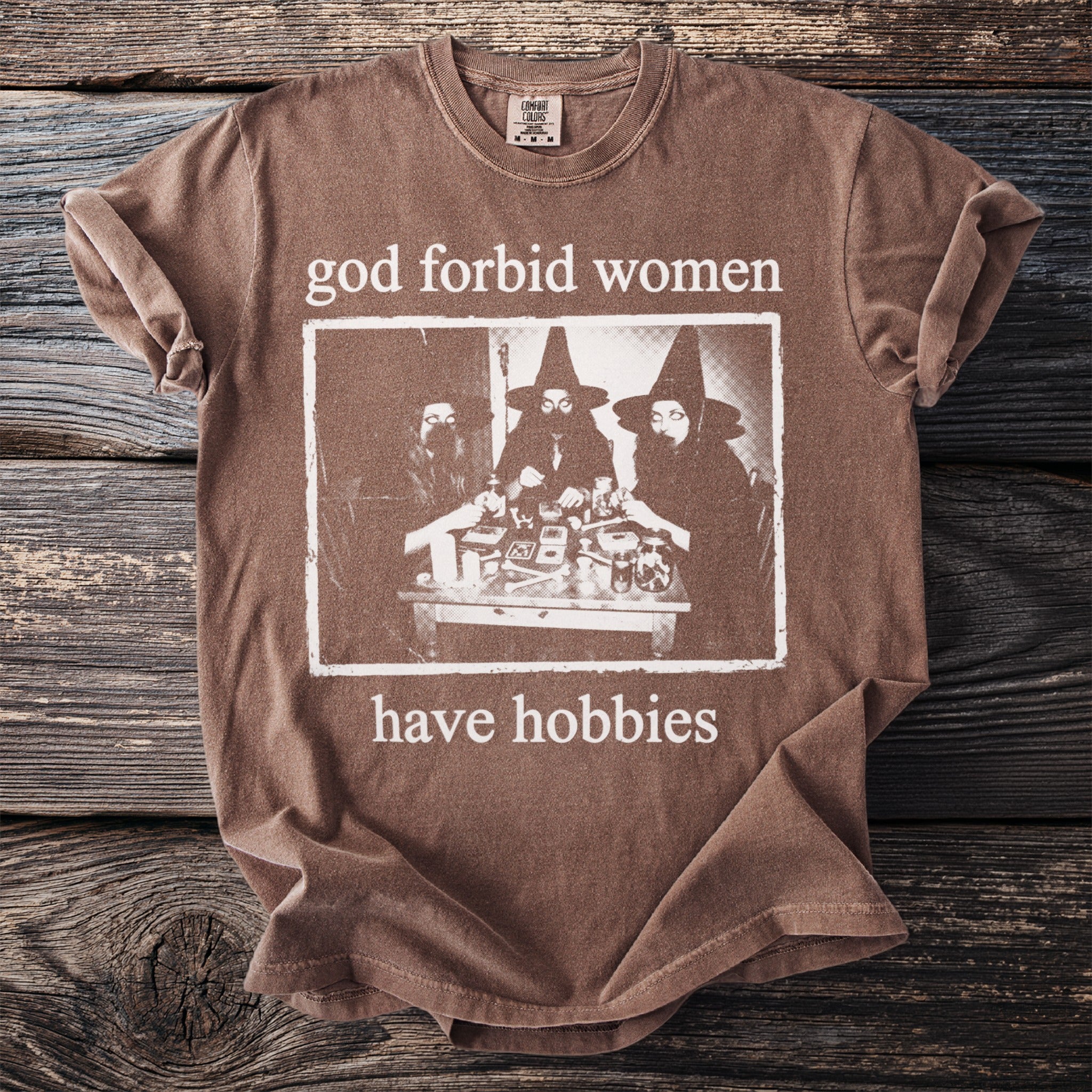 Brown t-shirt with "God forbid women have hobbies" and witch graphic.