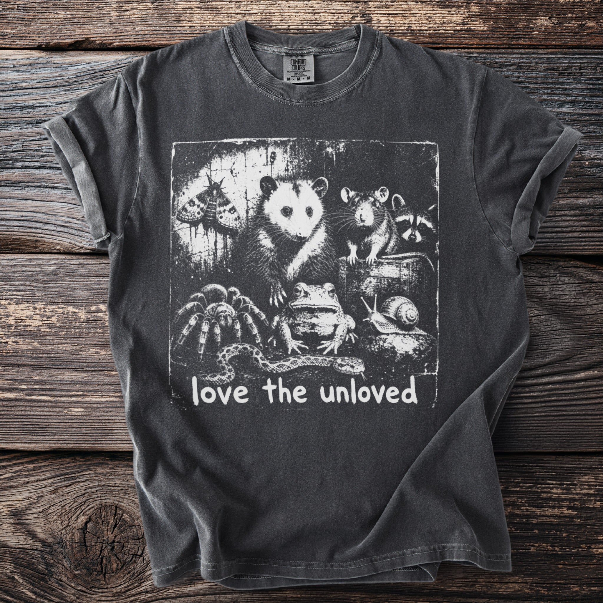 Dark t-shirt with a distressed print of an opossum, rat, raccoon, moth, frog, snake, spider, and snail, and text "love the unloved".
