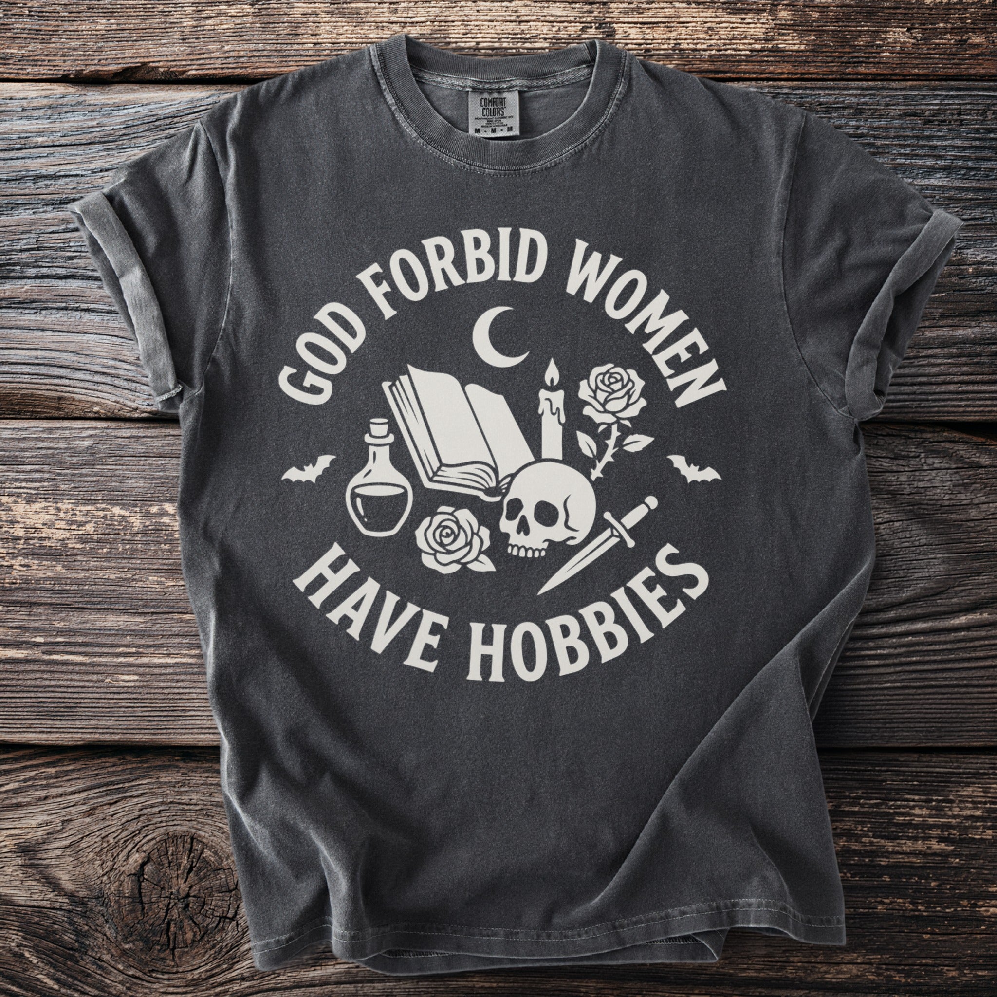 Dark grey t-shirt with "God forbid women have hobbies" and occult imagery.